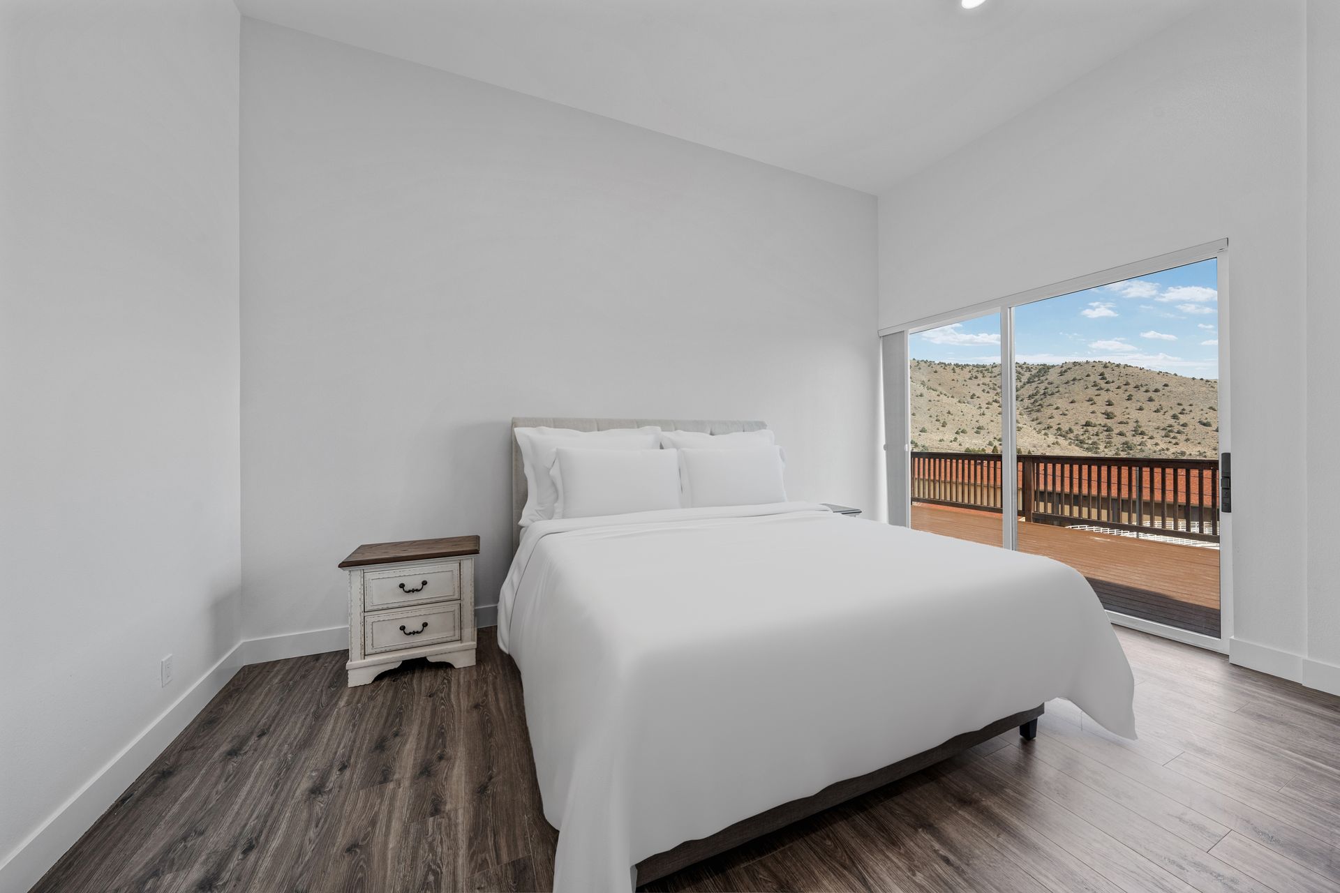 A bedroom with a bed , nightstand , and sliding glass doors.