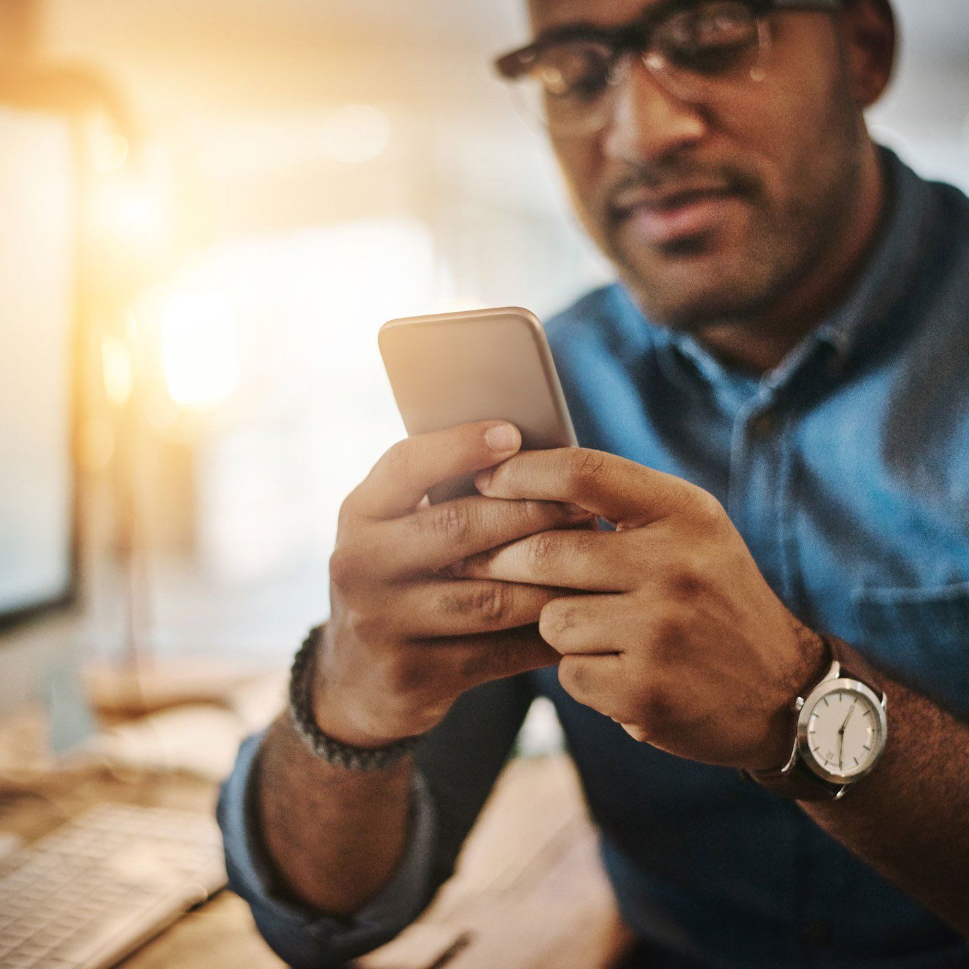 Cropped shot of a young businessman using a mobile phone during a late night at work