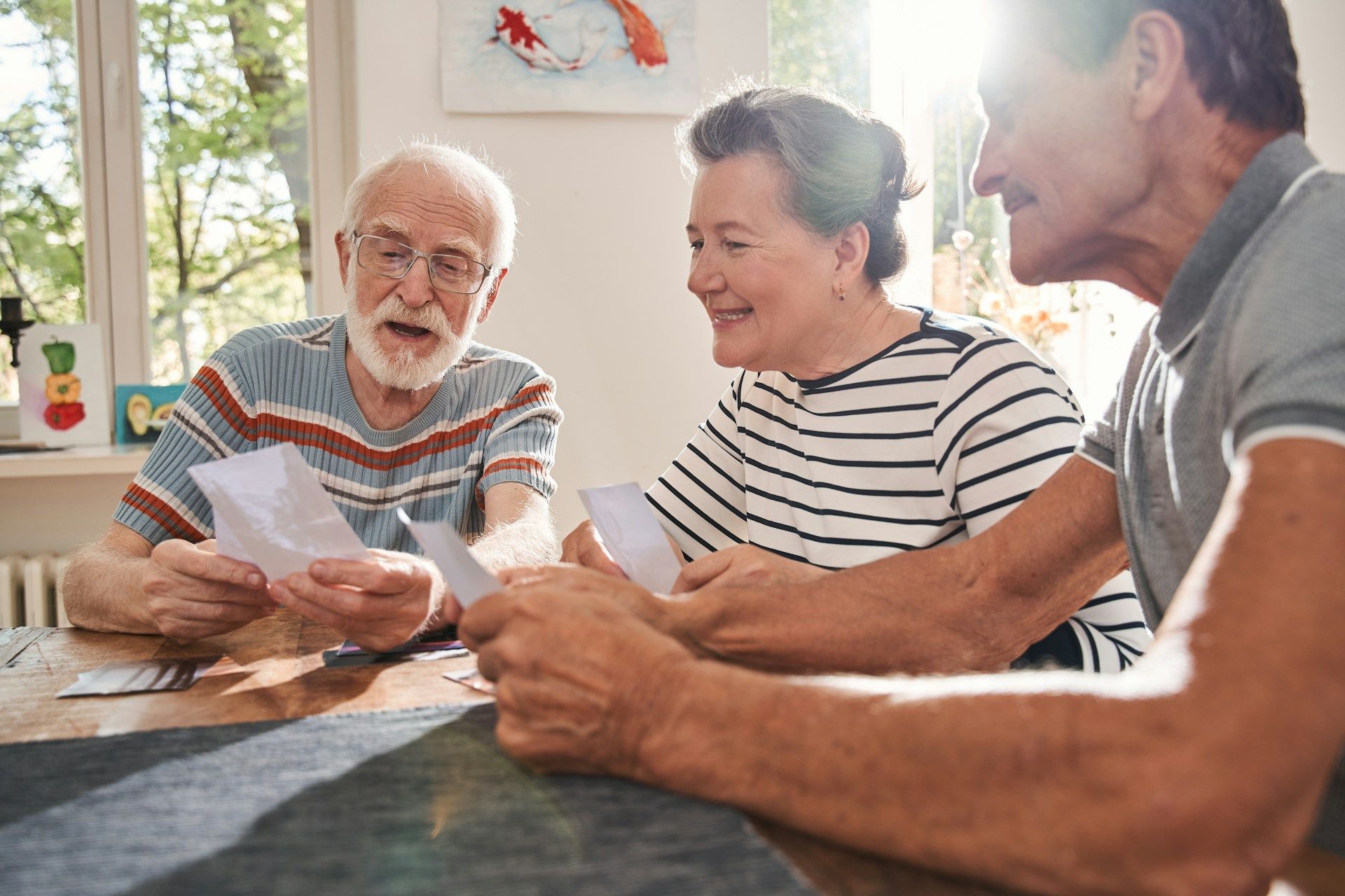 Three people reviewing papers together at a table in a bright kitchen