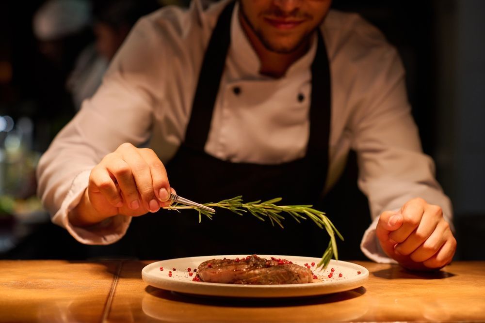 Chef Garnishing a Plate of Food With Rosemary; Kitchen Setting — Chefs2Go in Airlie Beach, QLD