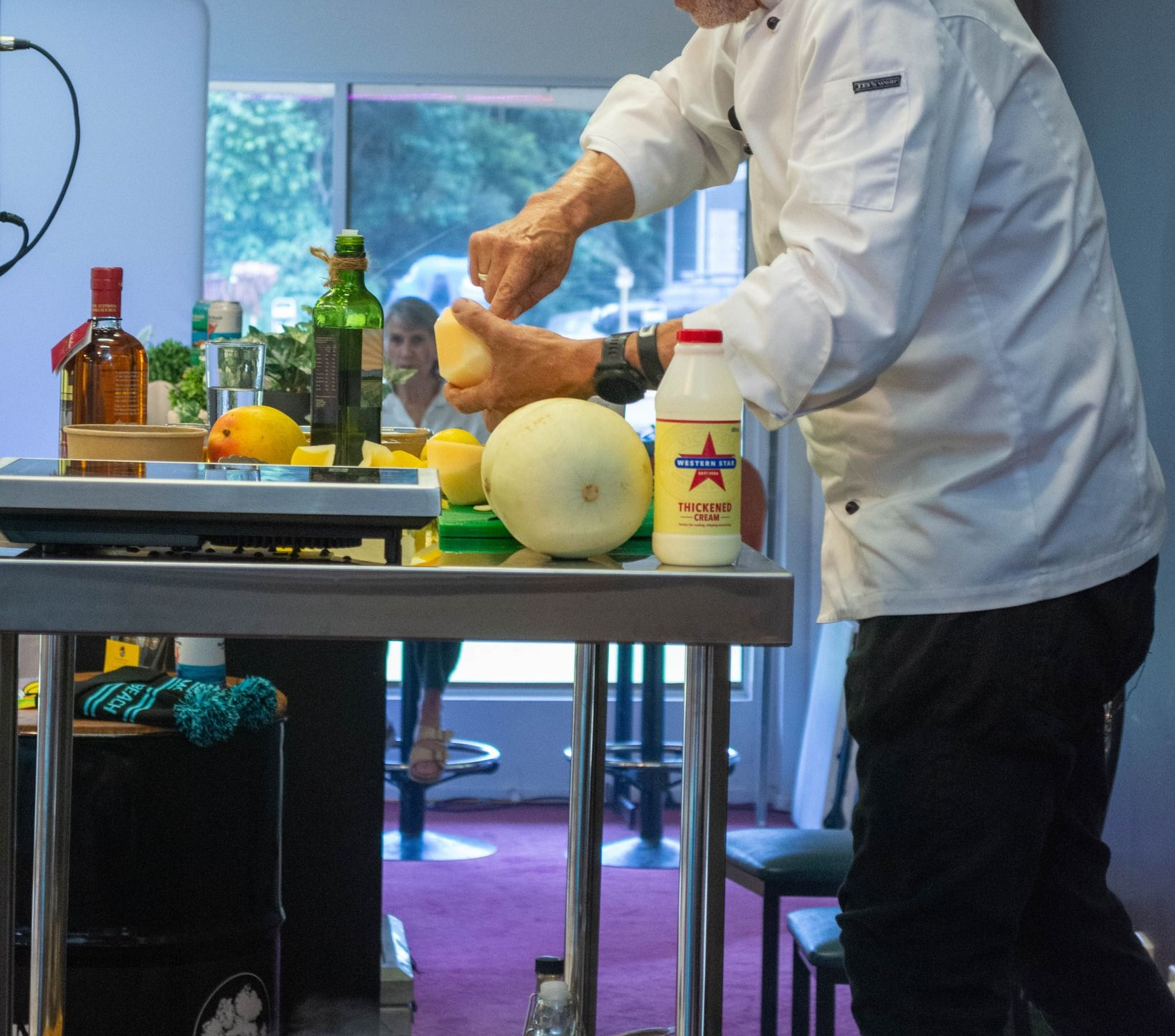 Chef in White Coat and Black Cap Preparing Food, Possibly a Cocktail, at a Bar — Chefs2Go in Cairns, QLD