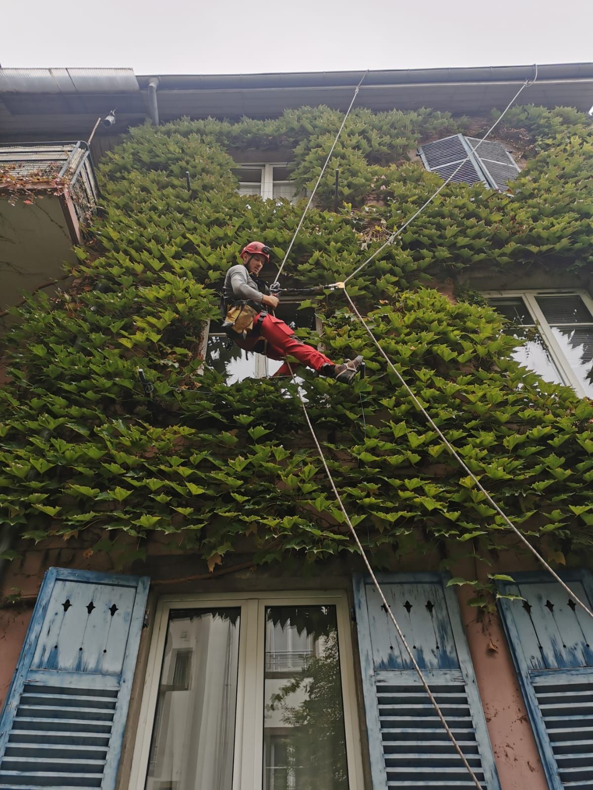 Un homme grimpe sur un bâtiment avec une corde.