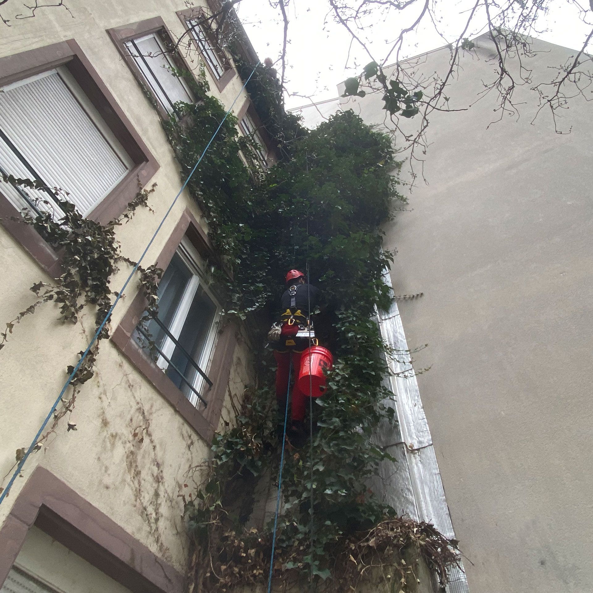 Un homme en veste rouge grimpe sur le côté d'un bâtiment