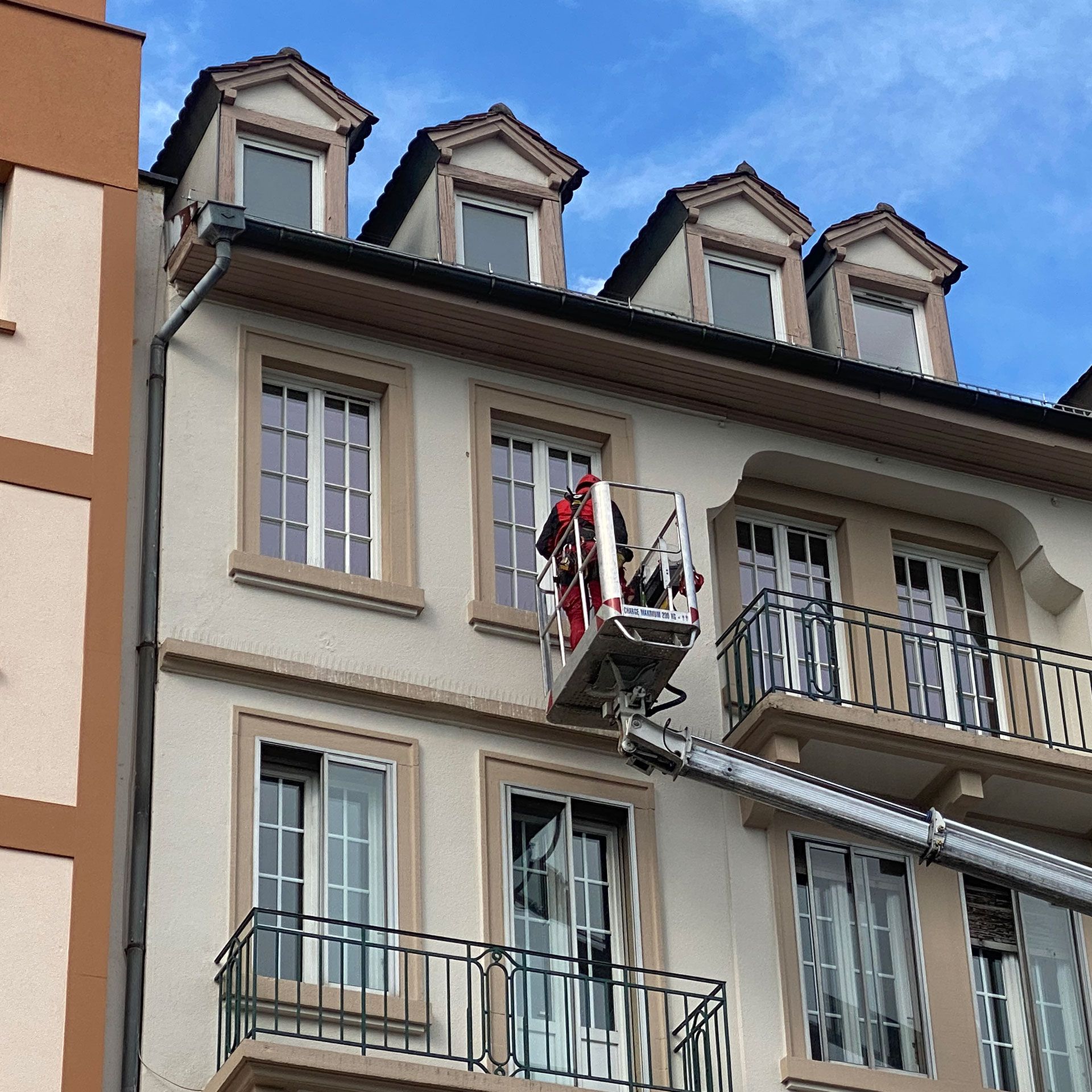 Un homme dans une grue nettoie les fenêtres d'un bâtiment