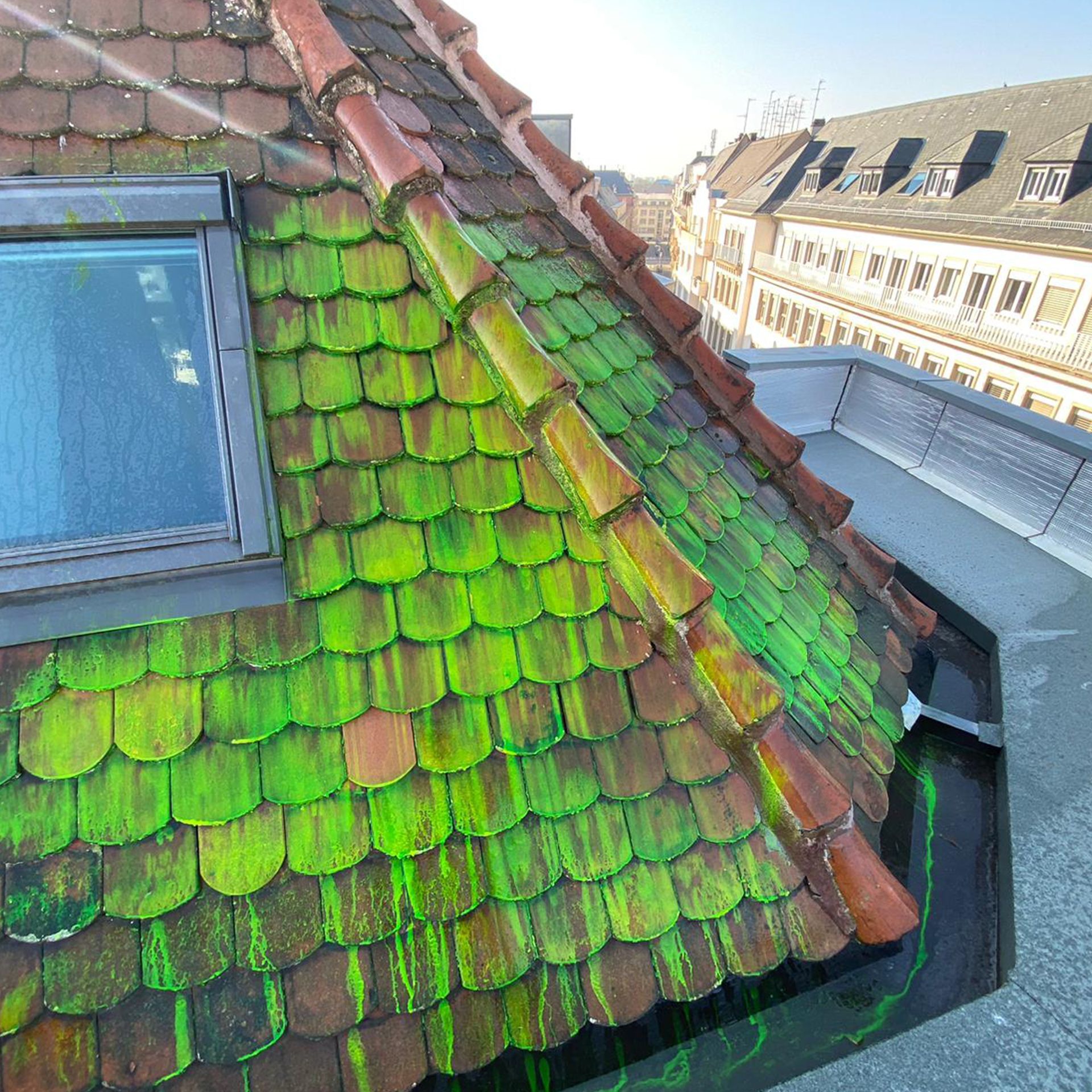 Un toit avec des tuiles vertes et une fenêtre dessus