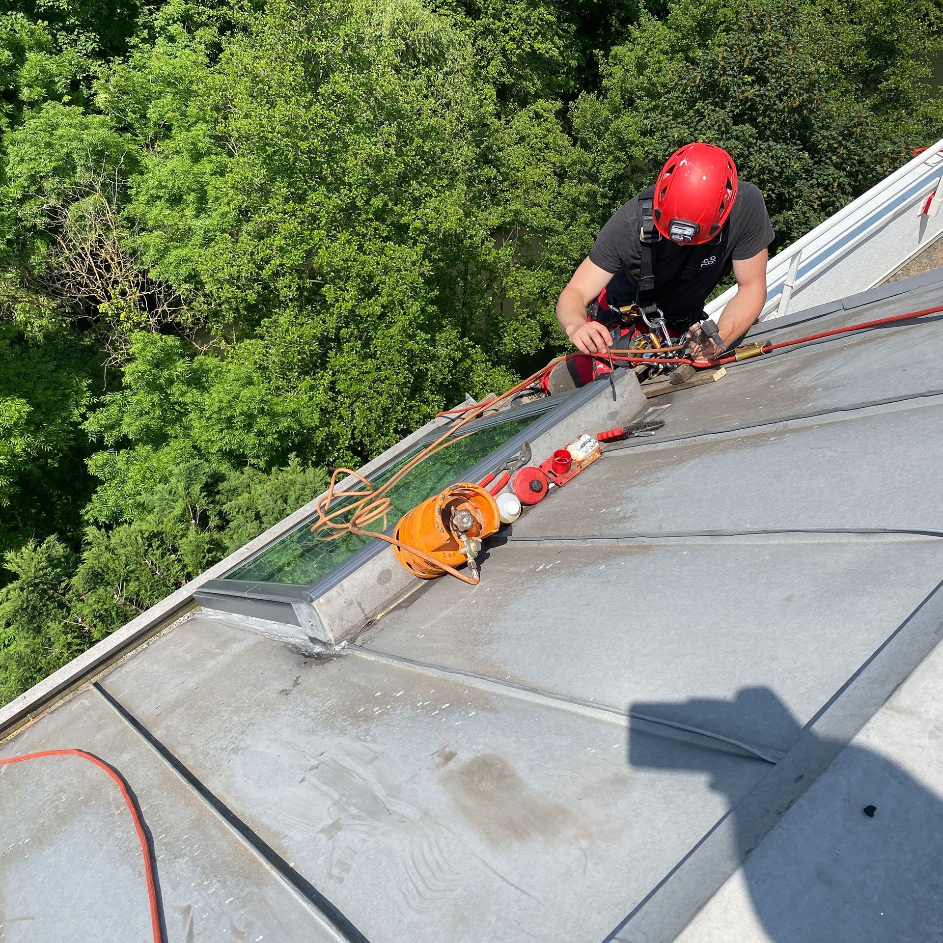 Un homme portant un casque rouge travaille sur un toit