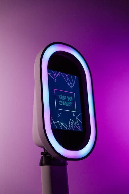 Alein open air photo booth with its ring light lit and a tap to start screen at a Denver event