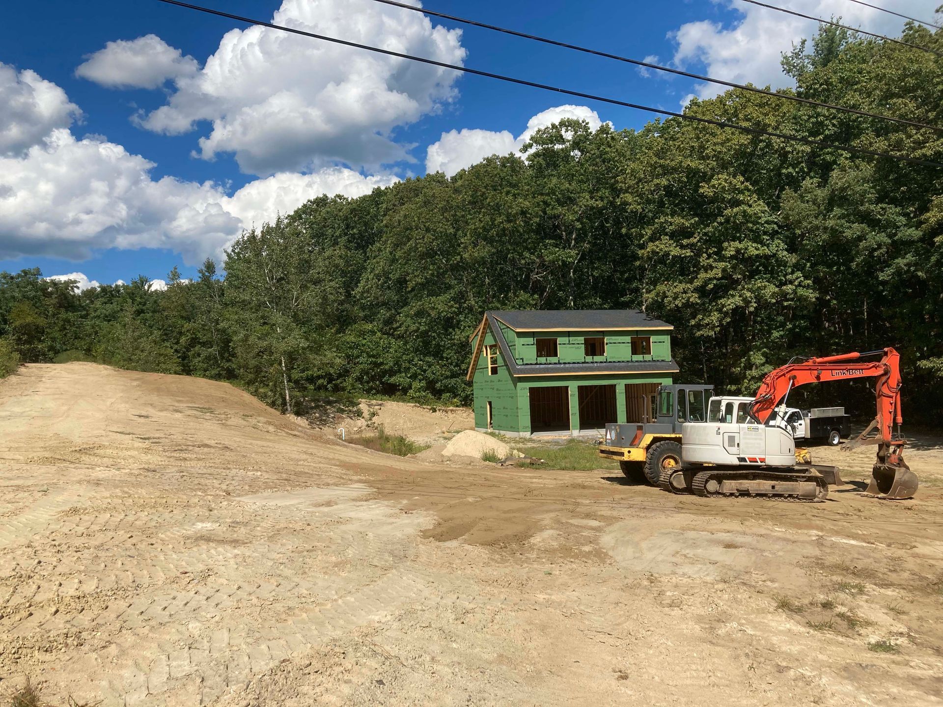 A construction vehicle is parked in front of a house under construction.