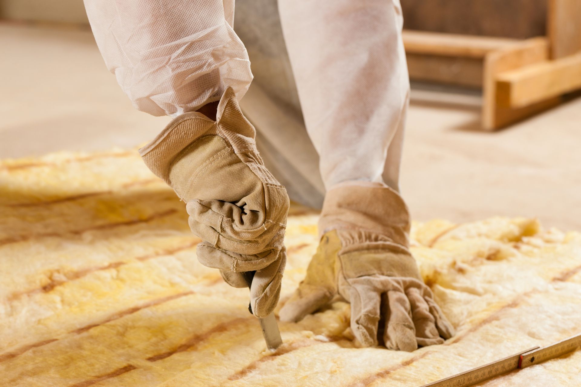 A person wearing gloves is cutting a piece of wood.