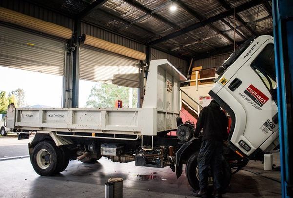 Mechanic Working on A White Dump Truck Inside a Garage โ DK Mechanical Repairs in Warners Bay, NSW
