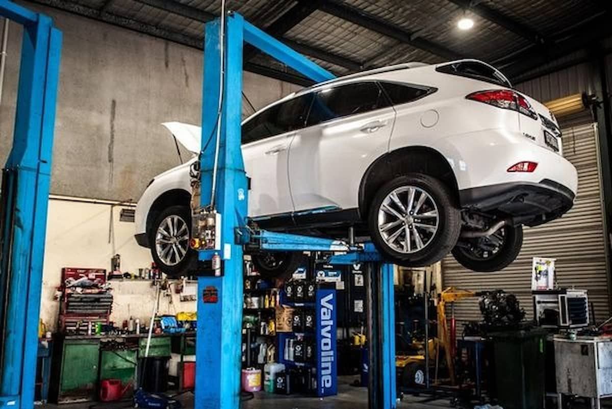 White Suv Raised on A Blue Car Lift in An Auto Repair Shop — DK Mechanical Repairs in Warners Bay, NSW