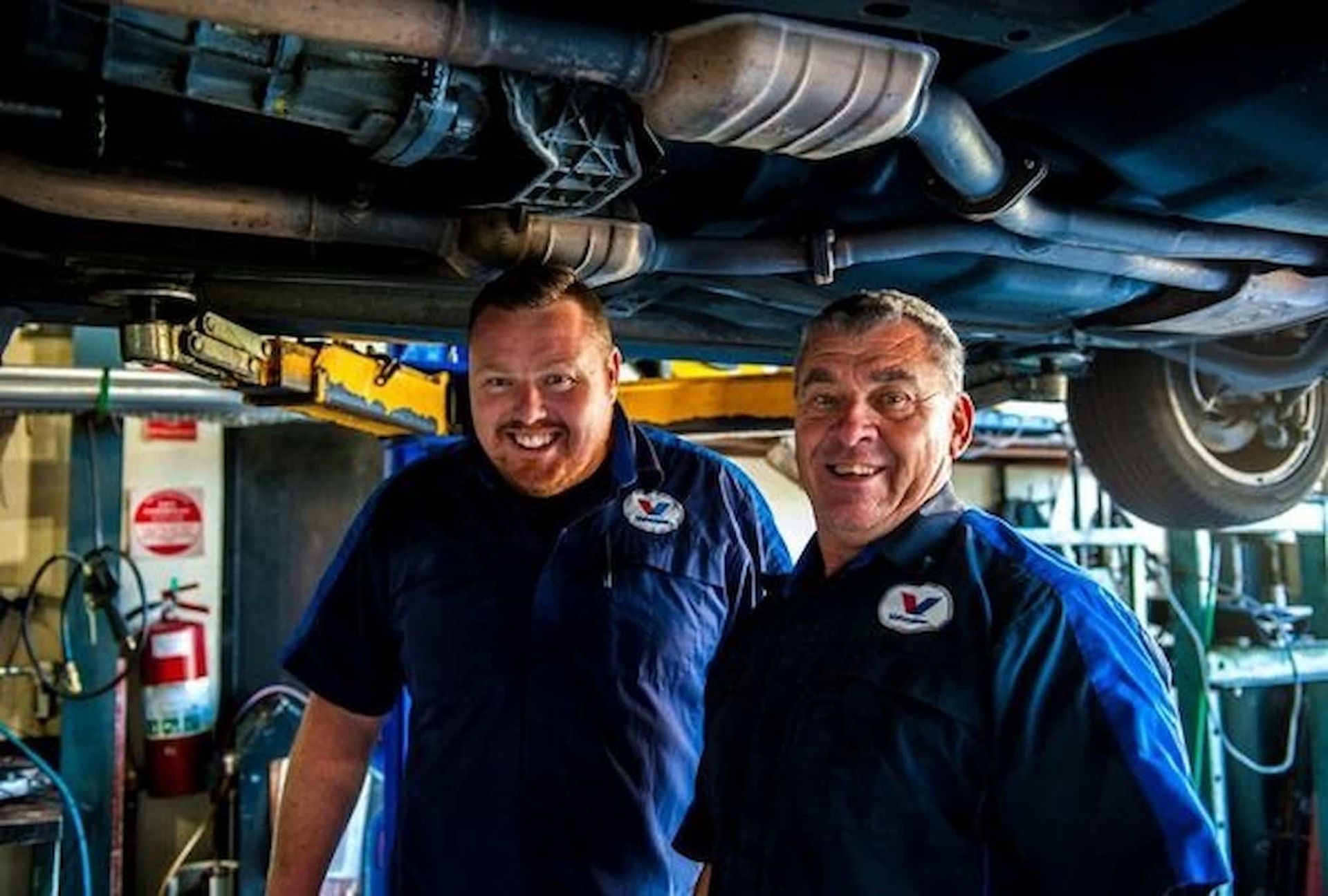 Two Mechanics Smiling Under a Car โ DK Mechanical Repairs in Warners Bay, NSW