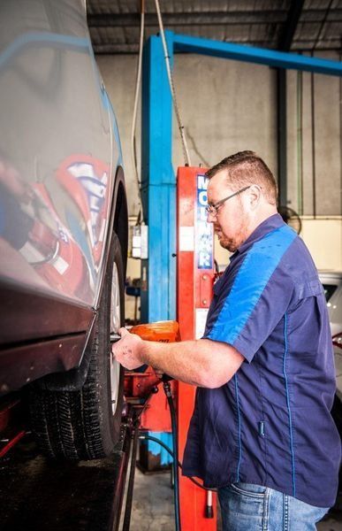 Mechanic Working on A Car Wheel with A Wrench — DK Mechanical Repairs in Warners Bay, NSW