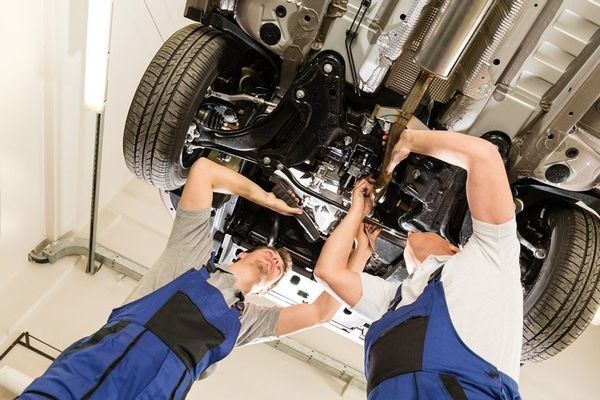 Two Mechanics in Blue Coveralls Working Under a Car โ DK Mechanical Repairs in Warners Bay, NSW