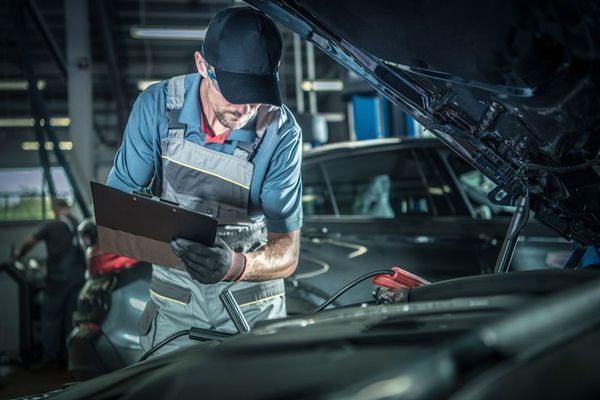 Mechanic in Overalls Inspecting a Car Engine with A Clipboard — DK Mechanical Repairs in Warners Bay, NSW