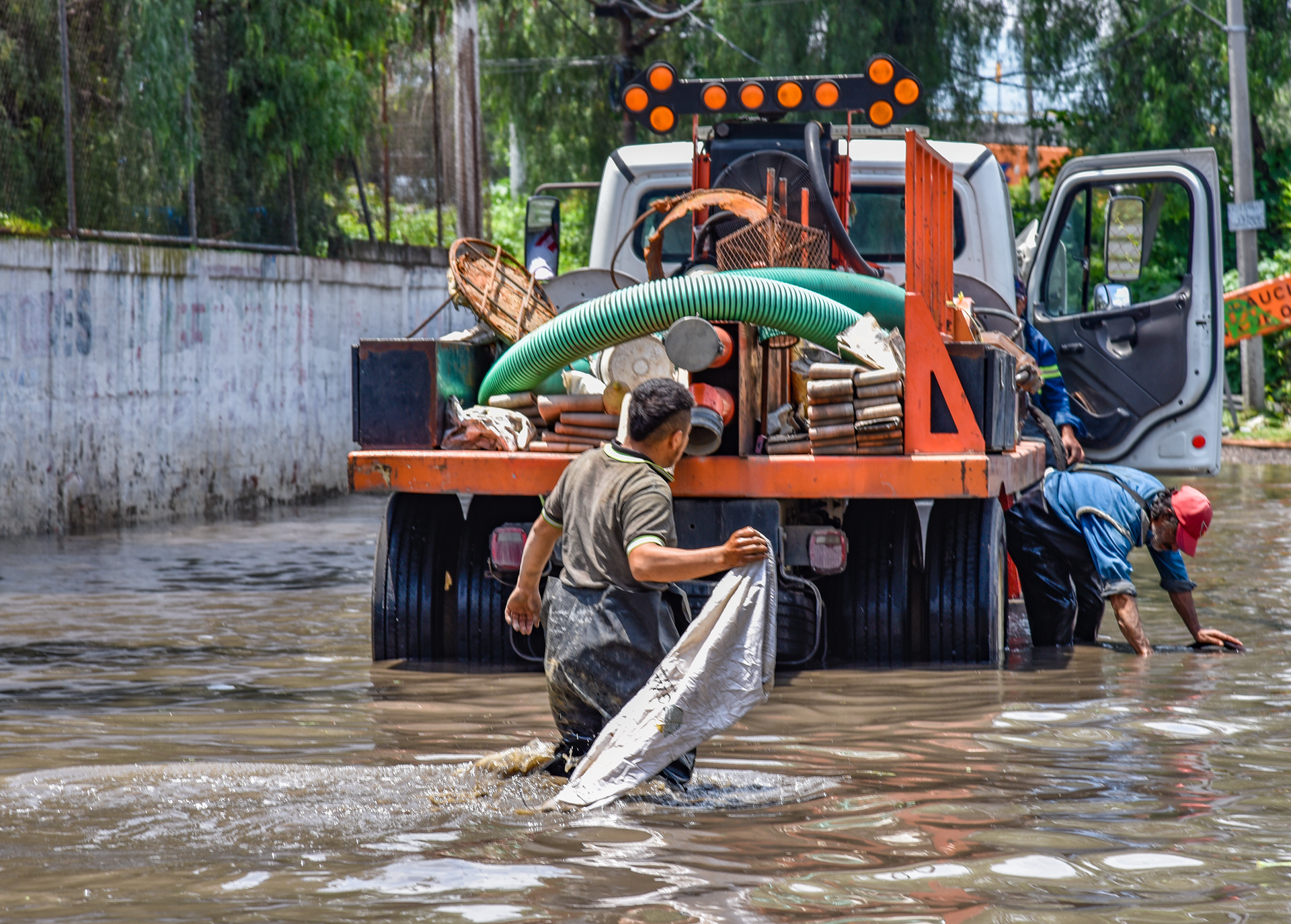 Worker installing a green circular manhole cover on a concrete base outdoors