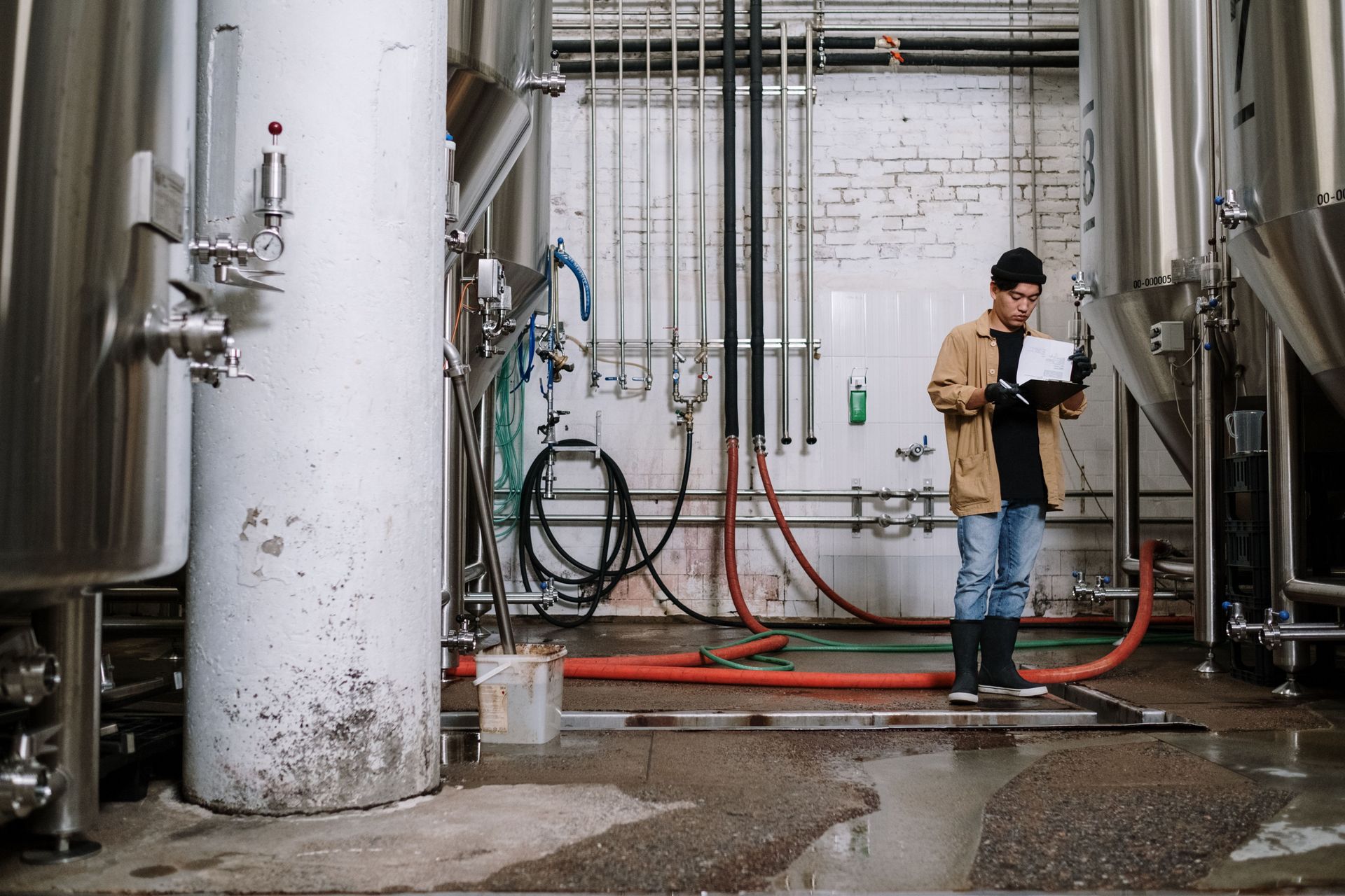 Worker in a neon vest repairing a hose or pipe in a grassy yard, with dirt piled nearby.
