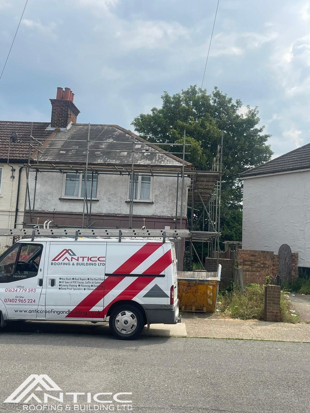 White van with red stripes parked outside a weathered house with scaffolding on the right