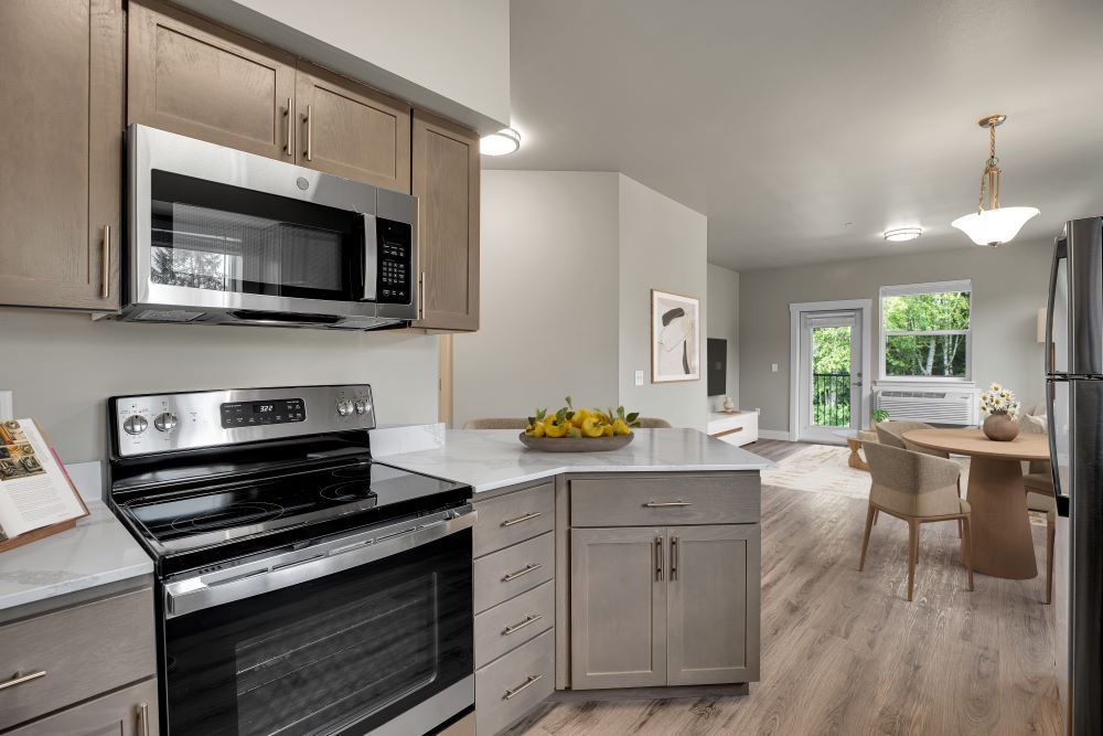 A kitchen with a stove, microwave, refrigerator, and cabinets.