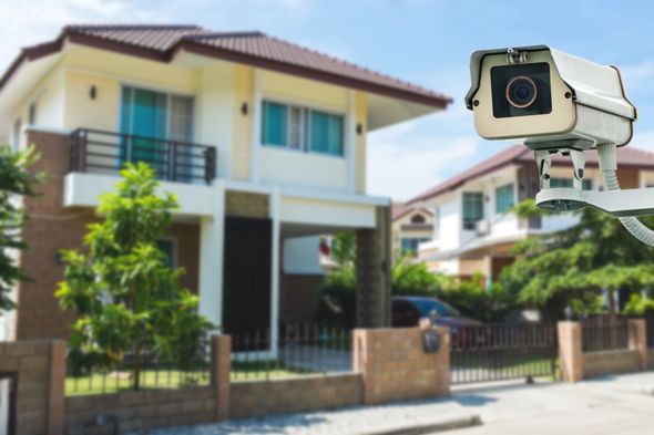 Telecamera di sicurezza installata all'esterno di una moderna casa di periferia con giardino anteriore recintato.