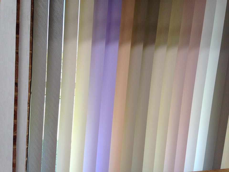 A Close Up of a Window With Vertical Blinds in Different Colors — Design 2000 Blinds & Awnings In San Remo, NSW