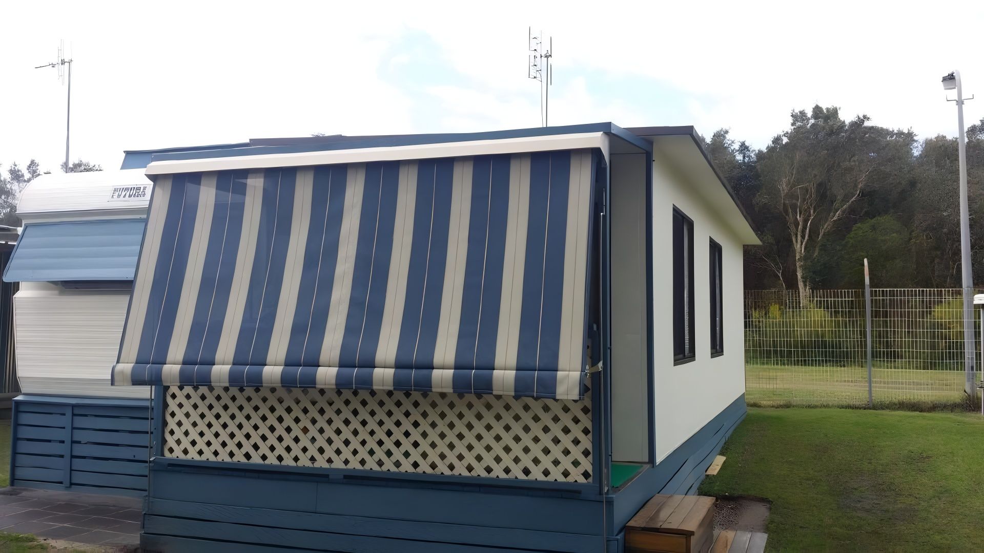 A Mobile Home With a Blue and White Striped Awning — Design 2000 Blinds & Awnings In San Remo, NSW
