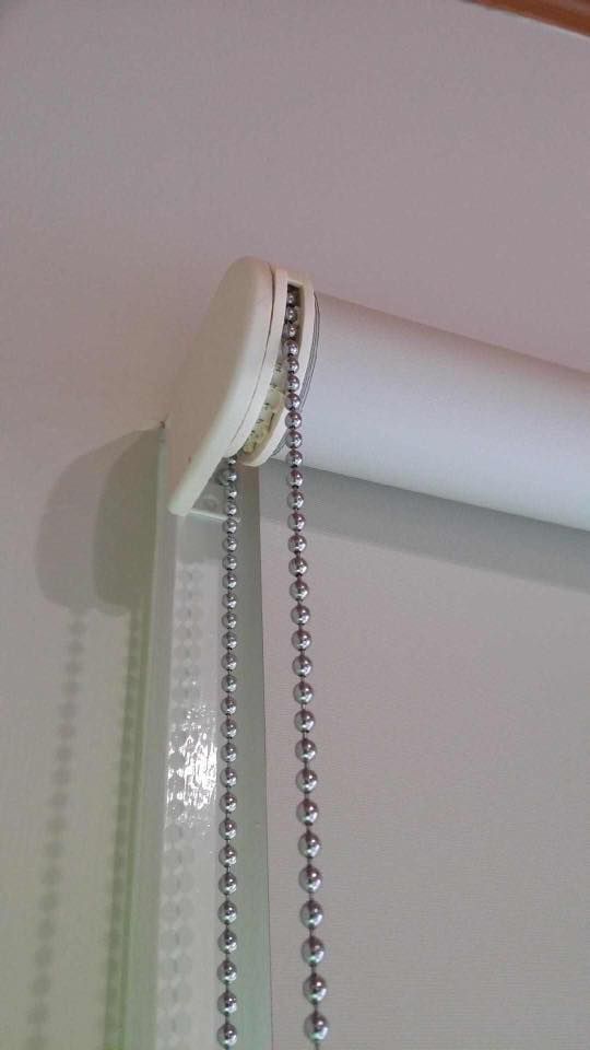 A Close Up of a Roller Blind With a Chain Attached to It — Design 2000 Blinds & Awnings In San Remo, NSW