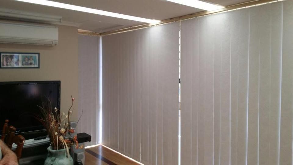 A Living Room With White Vertical Blinds and a Tv — Design 2000 Blinds & Awnings In San Remo, NSW