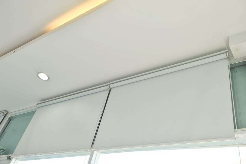A Close Up of a White Roller Blind on a Window — Design 2000 Blinds & Awnings In San Remo, NSW
