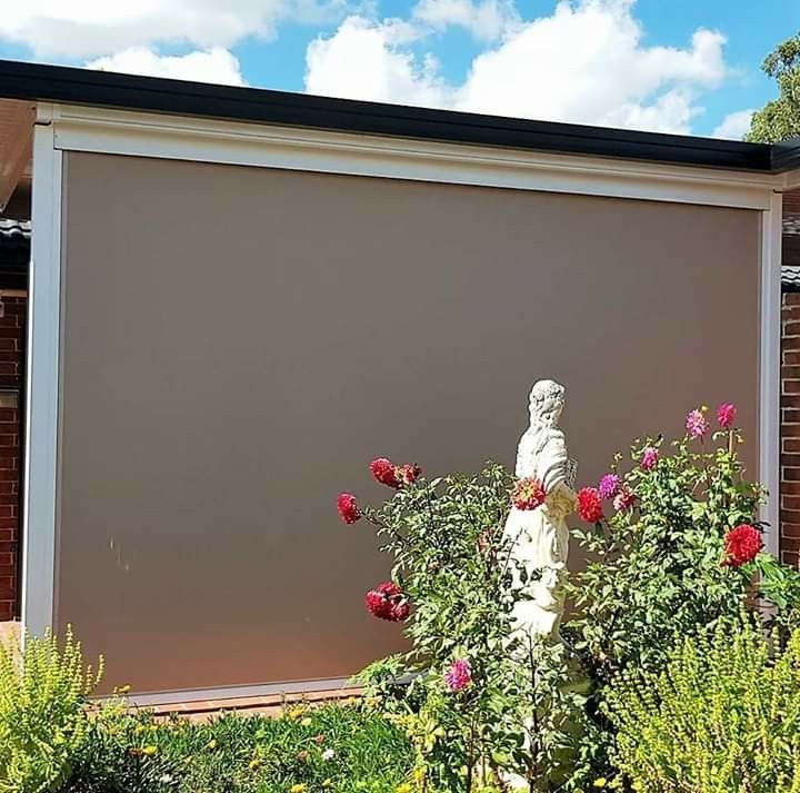 A Statue is Standing in Front of a Large Screen in a Garden — Design 2000 Blinds & Awnings In San Remo, NSW