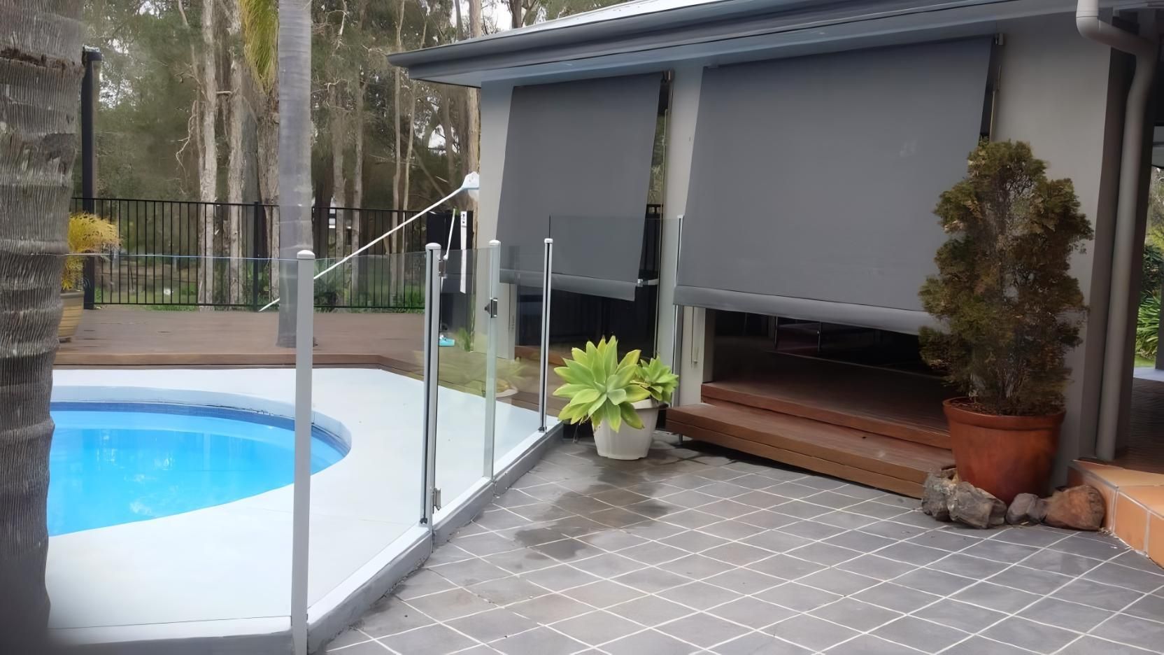 There is a Swimming Pool in the Backyard of a House — Design 2000 Blinds & Awnings In San Remo, NSW