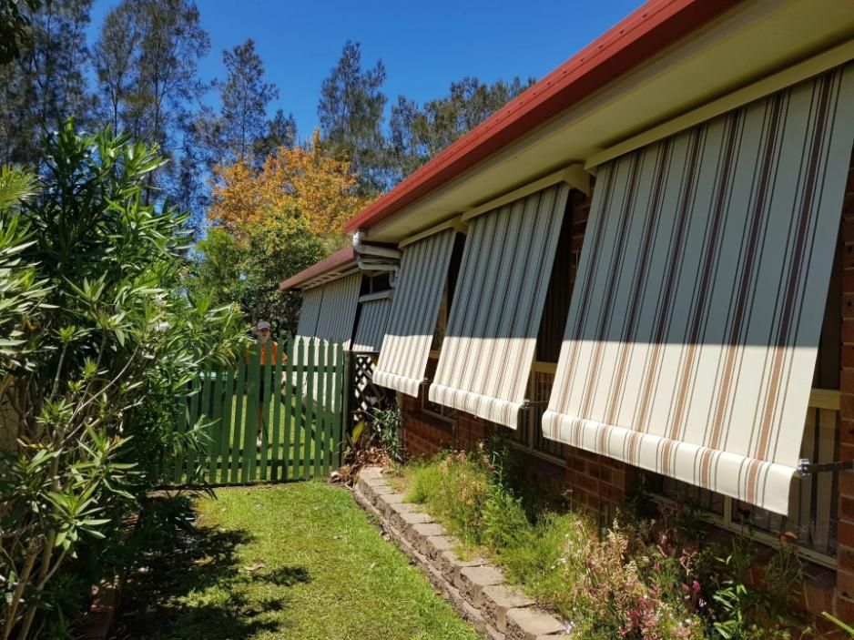 A House With Striped Awnings on the Side of It — Design 2000 Blinds & Awnings In San Remo, NSW