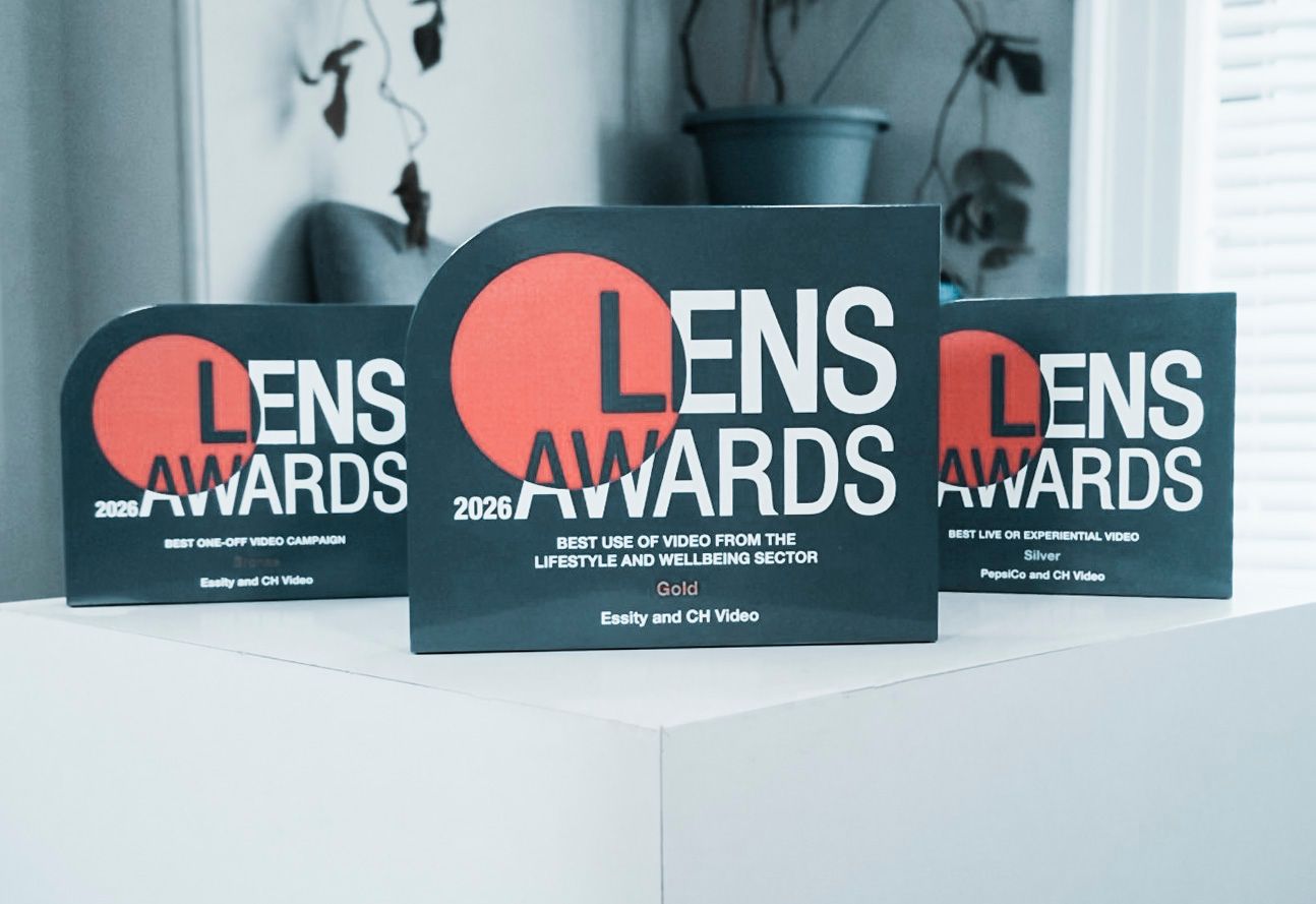 Lens Awards plaques on a white table, black and red design with a blurred office background