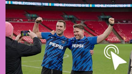 Two Pepsi-shirted players raise their arms on a soccer field, celebrating in a stadium.