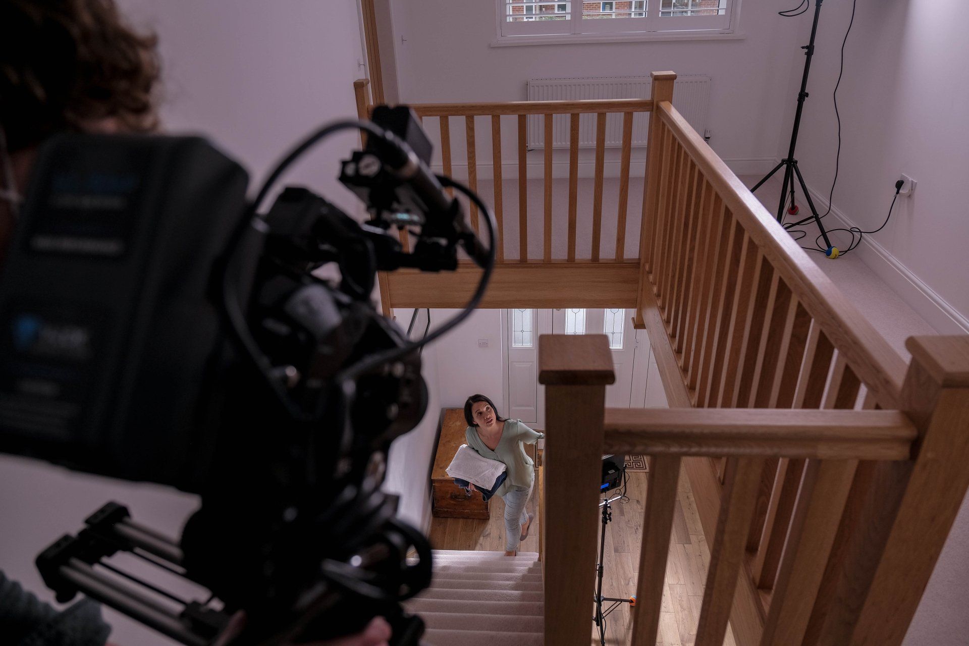 A camera is being used to film a woman walking down stairs.
