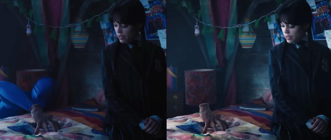 A woman is standing next to a bed in a dark room.
