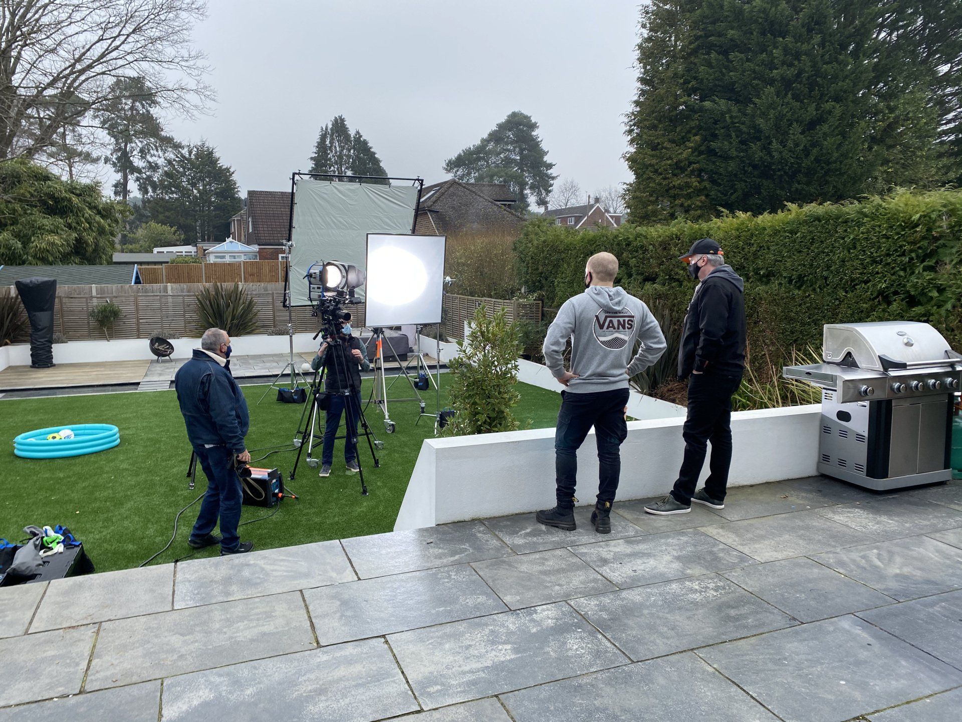 A group of men are standing on a patio in front of a camera.