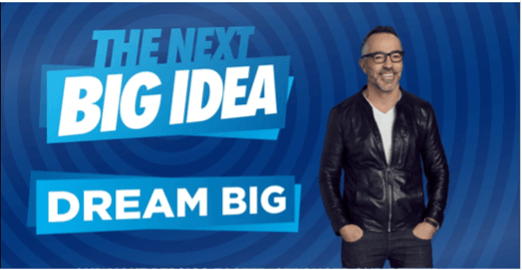 A man stands in front of a sign that says the next big idea dream big