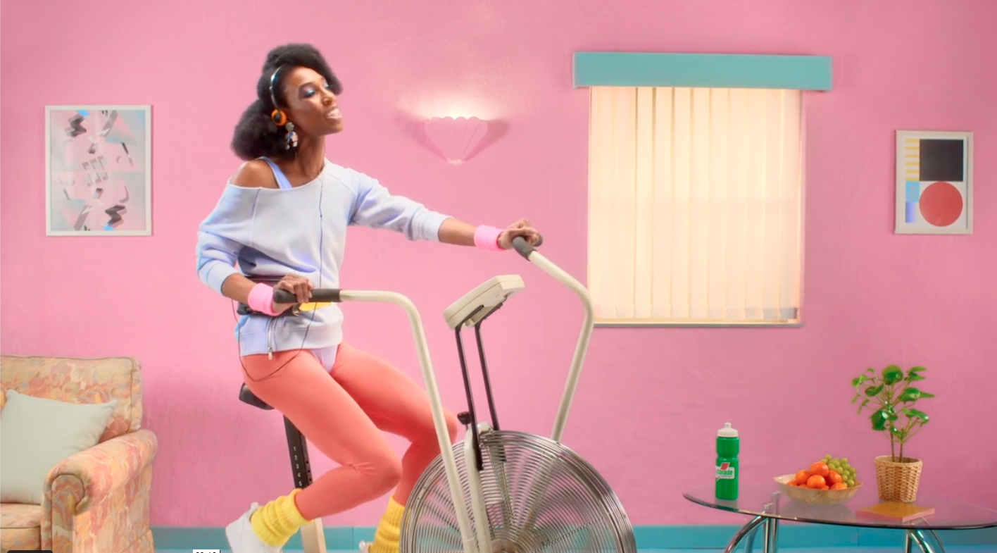 A woman is riding an exercise bike in a pink room.