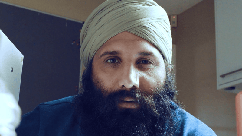 A man with a beard and turban is holding a piece of paper.