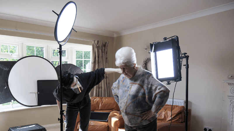 A man is taking a picture of an older woman in a living room.
