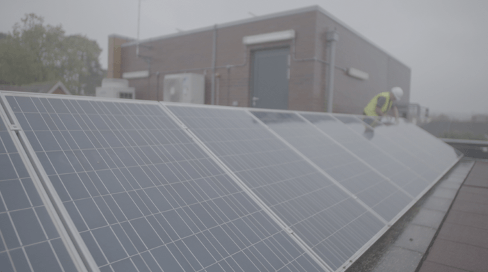 A man is installing solar panels on the roof of a building.