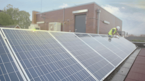 A man is installing solar panels on the roof of a building.