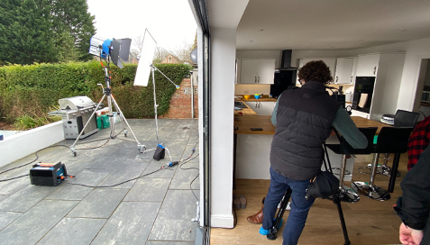 A man is standing in front of a camera in a kitchen.