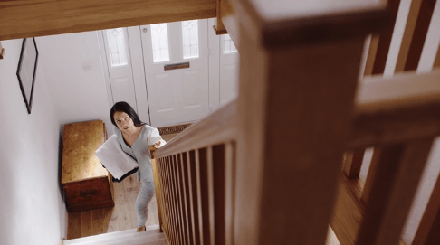 A woman is walking down a set of stairs holding a piece of paper.