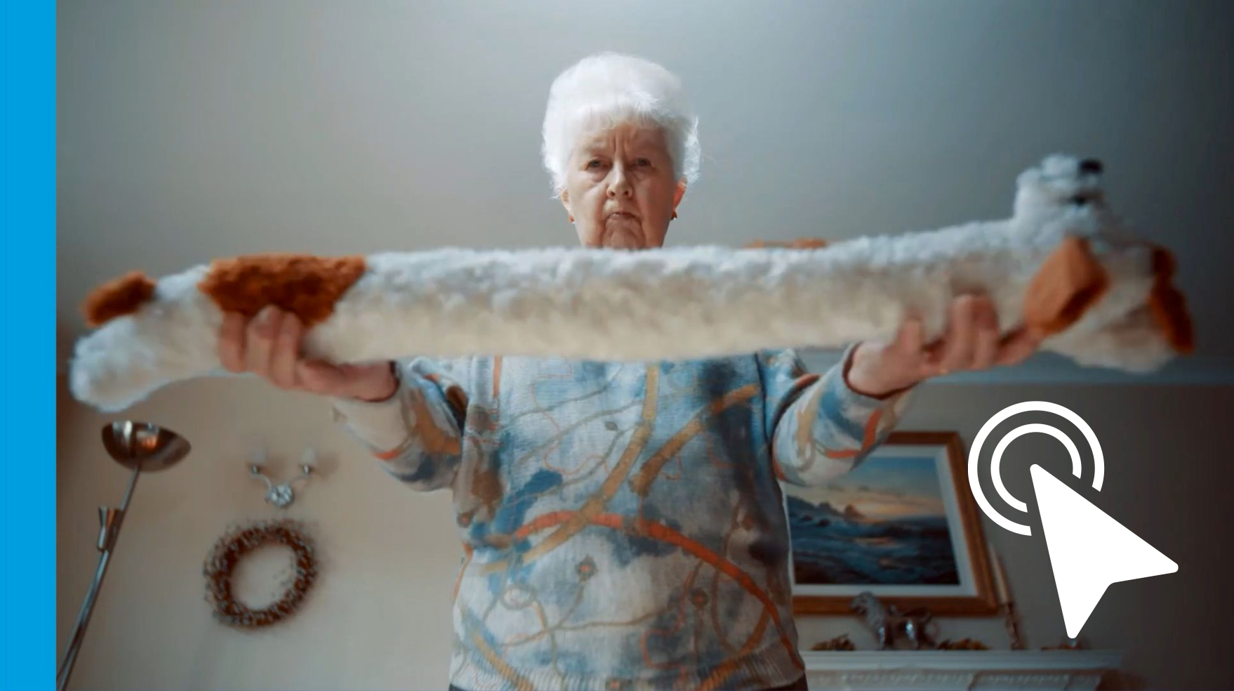 Person holding a long white cat horizontally indoors, with a white pointer cursor overlay.