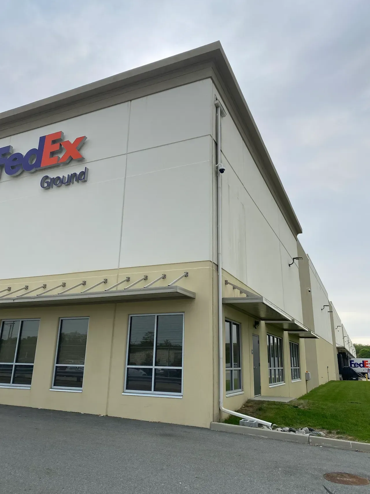 FedEx Ground warehouse exterior with beige walls and large windows under a cloudy sky