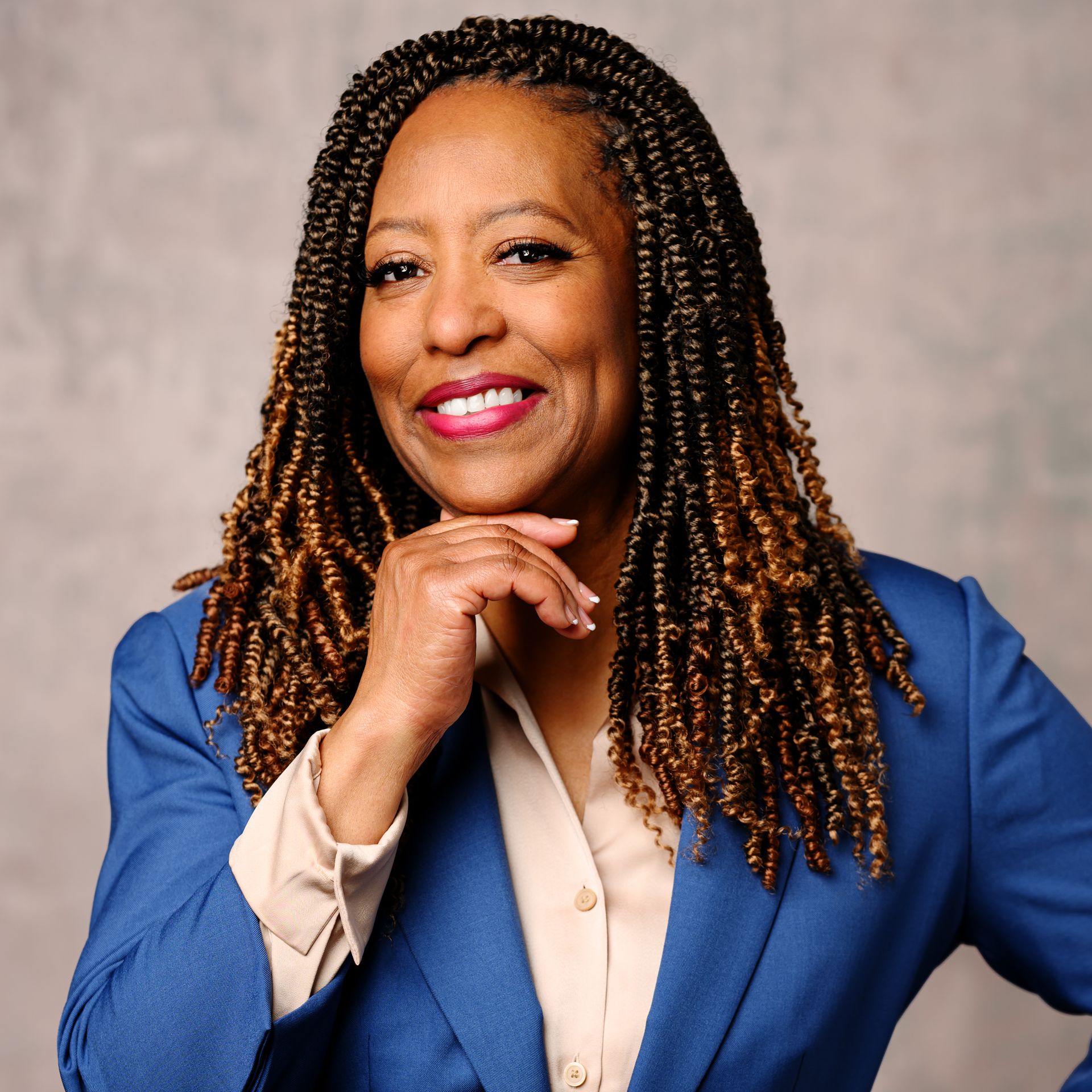 A woman with long black hair is standing in front of a wooden fence.