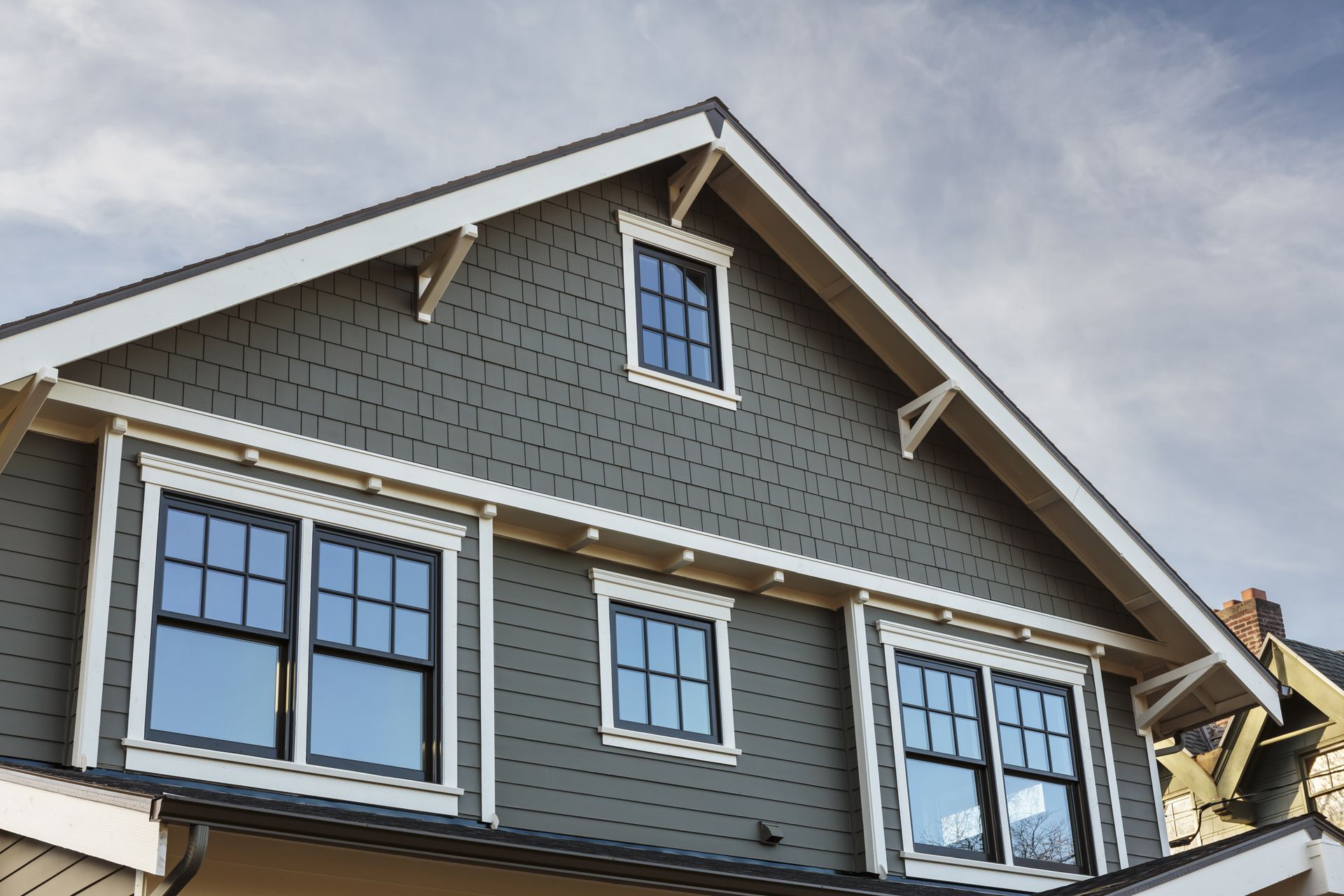 Gray house exterior with white-trimmed windows and gabled roof