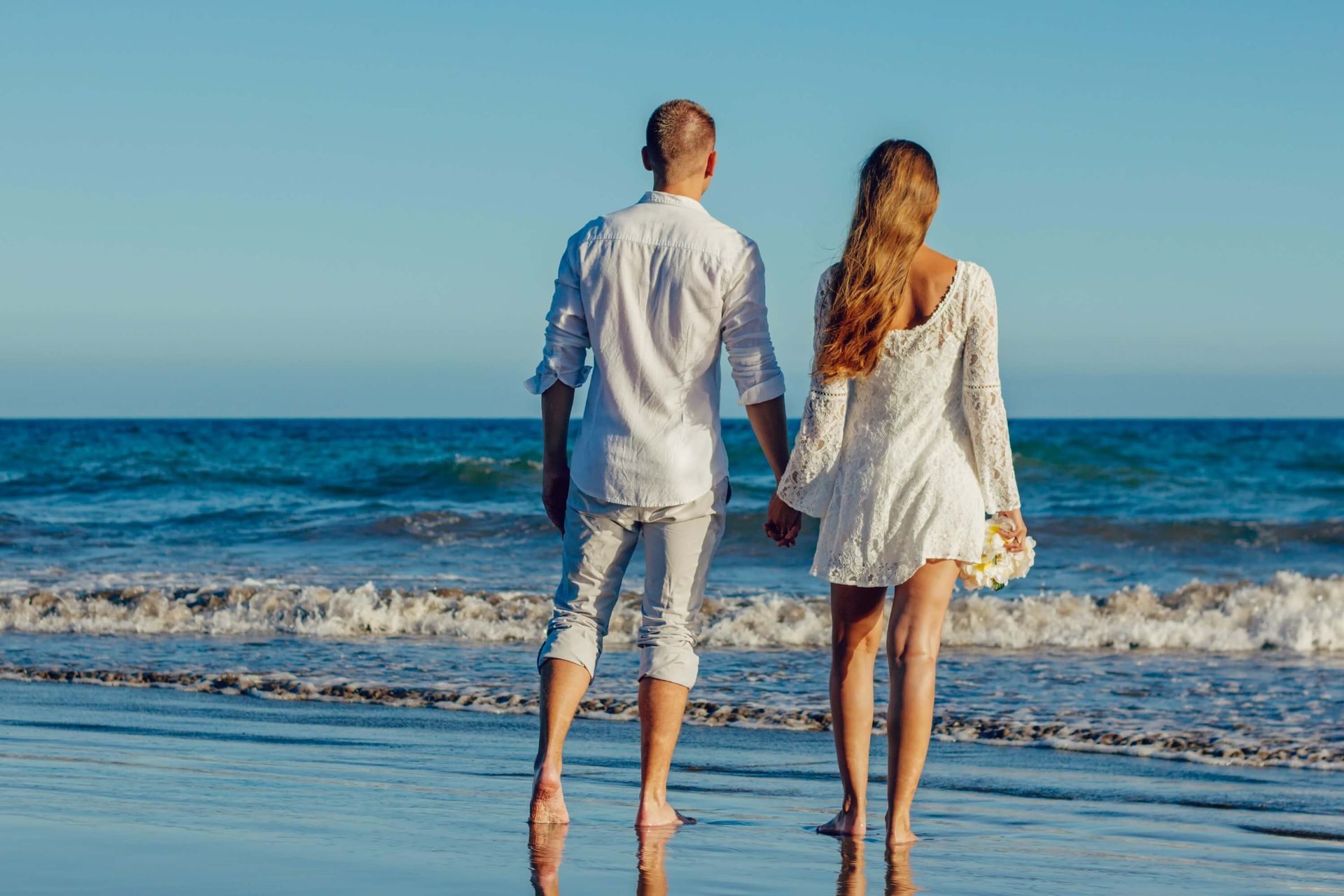 A couple holds hands as the watch the waves roll in. Improve your communication and connection with a Retreat for Couples in Orlando, FL. Couples Retreats are available to couples in Florida, North Carolina, Virginia, and beyond.